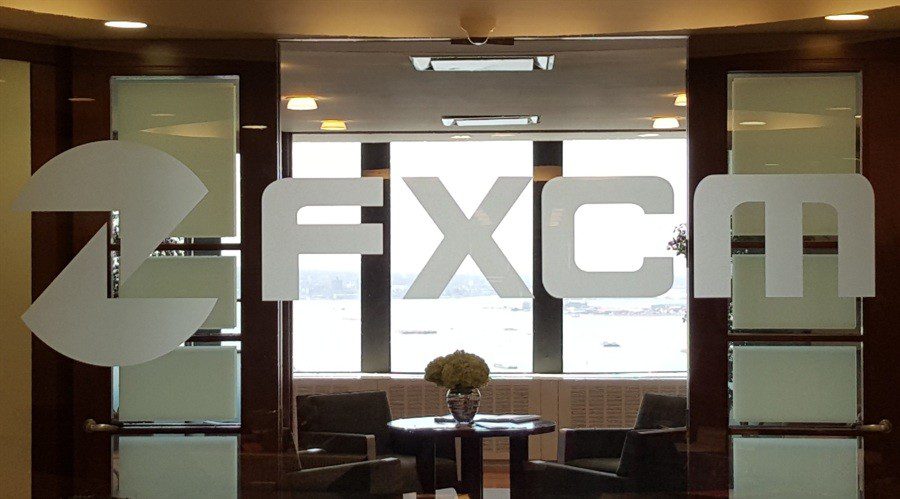 FXCM logo in front of a forex and CFD trading desk